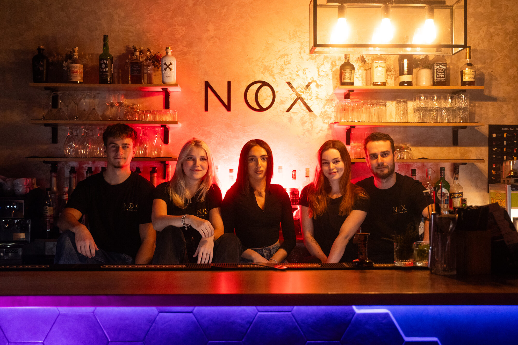 Tím NOX za podsvieteným barovým pultom