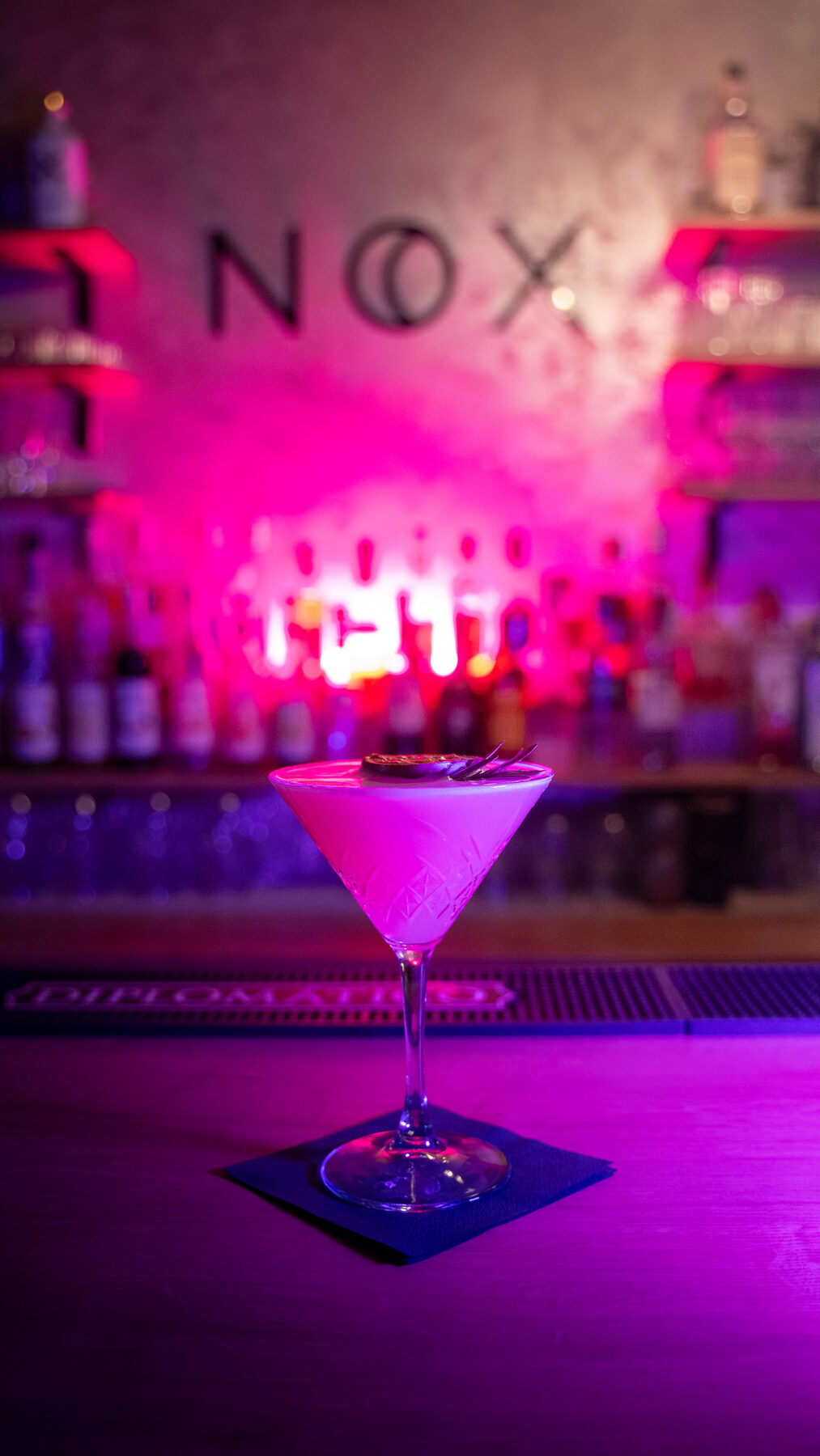 Signature martini cocktail na bare v ružovom svetle
