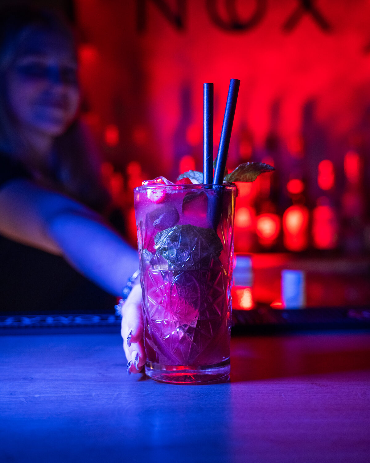 Barmanka podáva ovocný cocktail v červenom svetle